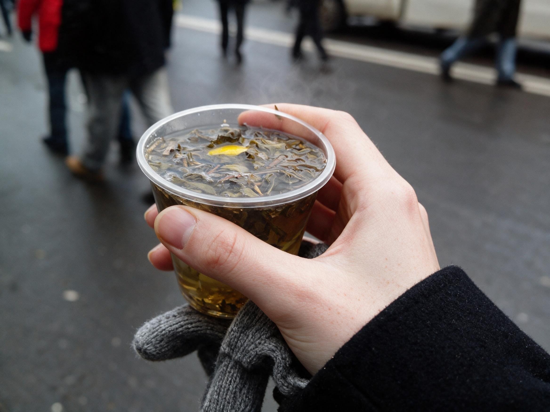 My gloved hand, a steaming plastic cup of tea, snowy Kyiv blurred behind.