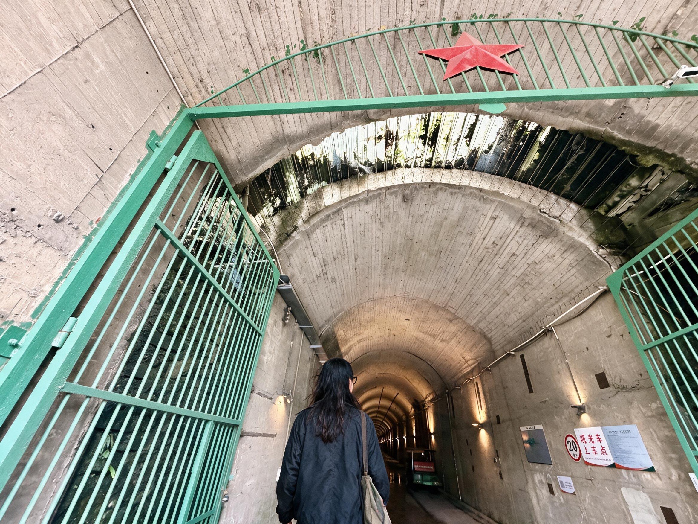 Me walking into the huge concrete tunnel of Project 816, mint-green gates open, red star above.