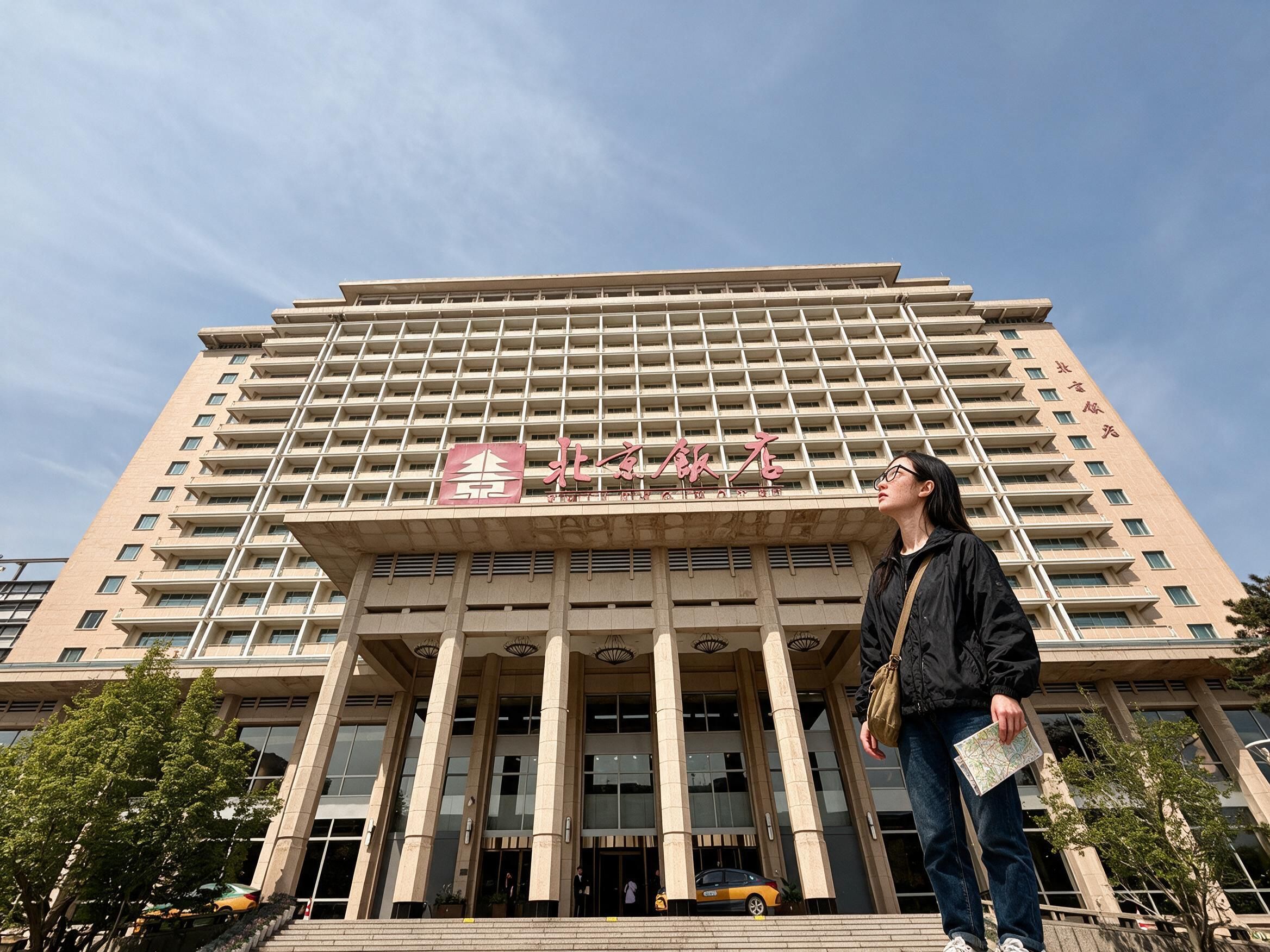 Me on the front steps of the Beijing Hotel with a folded map, looking up at the facade.