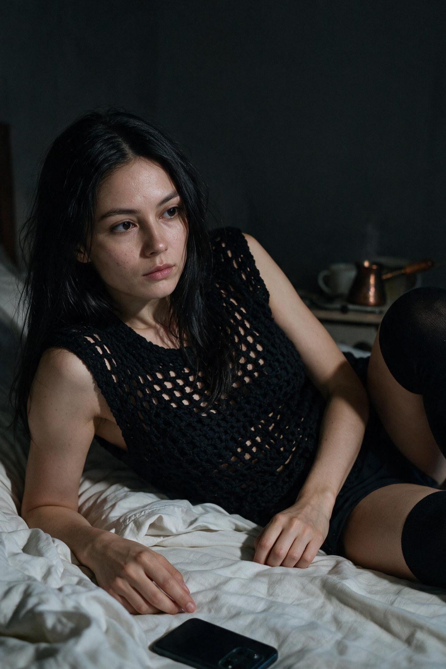 On the bed after a call home: crochet vest, overknees, phone face down, cezve still warm.