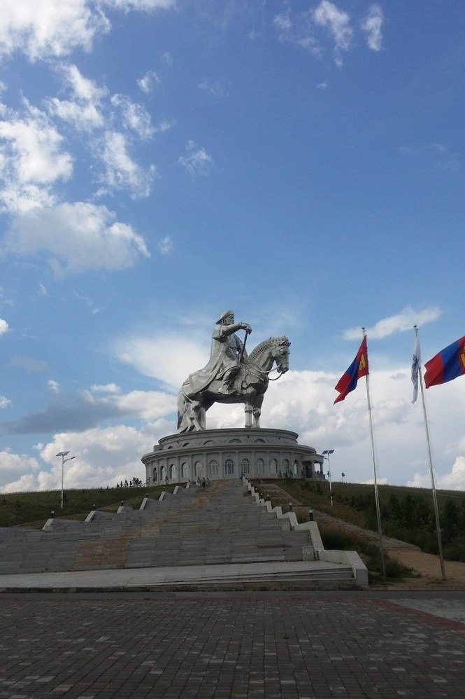 Giant steel Genghis Khan statue on the steppe, flags flying before it.