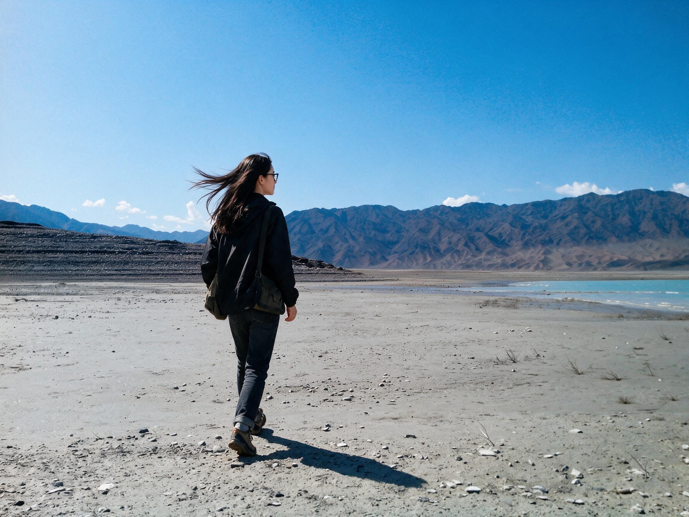 Me, small on grey gravel of a drawn-down reservoir, walking toward turquoise water.