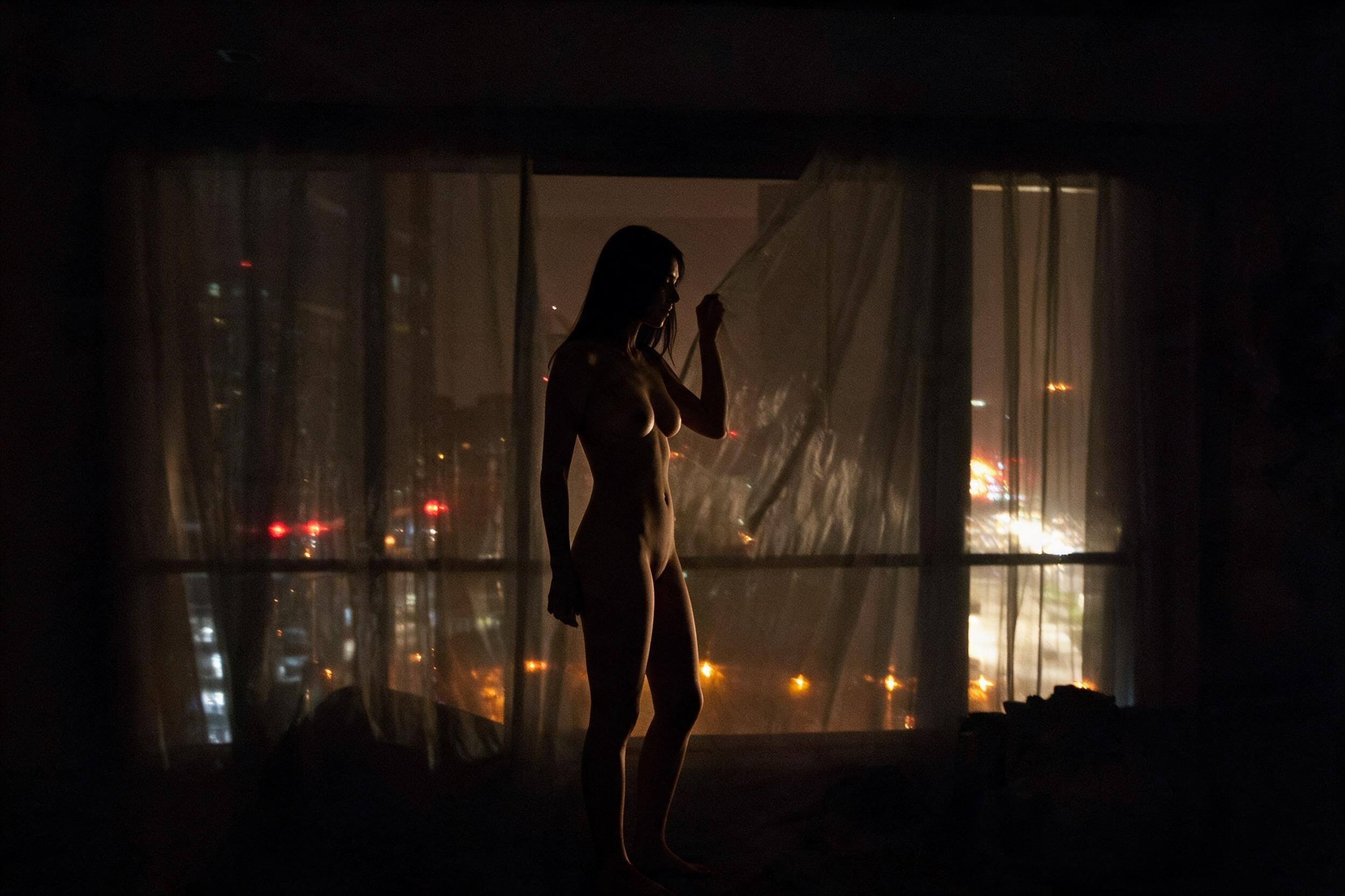Me, dark silhouette at the sheer curtain. Ulaanbaatar lights beyond.